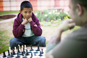 an adult man  playing chess with young boy