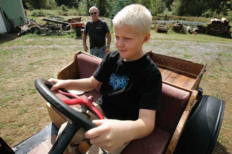 Roy VanBuskirk (background) watches his grandson, Brandon VanBuskirk, at the wheel of a Model A they restored together. (The Dispatch) 