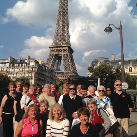 With the Eiffel Tower in the background, a group of American travelers pose for a photo during a visit to Paris.